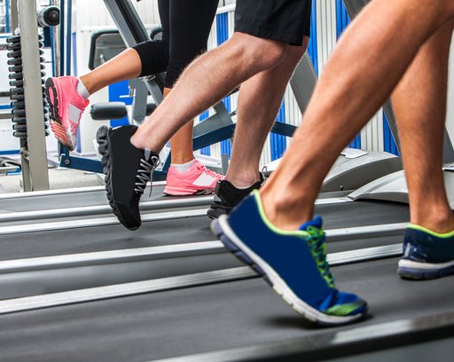 Group of legs wearing sneakers running on treadmill