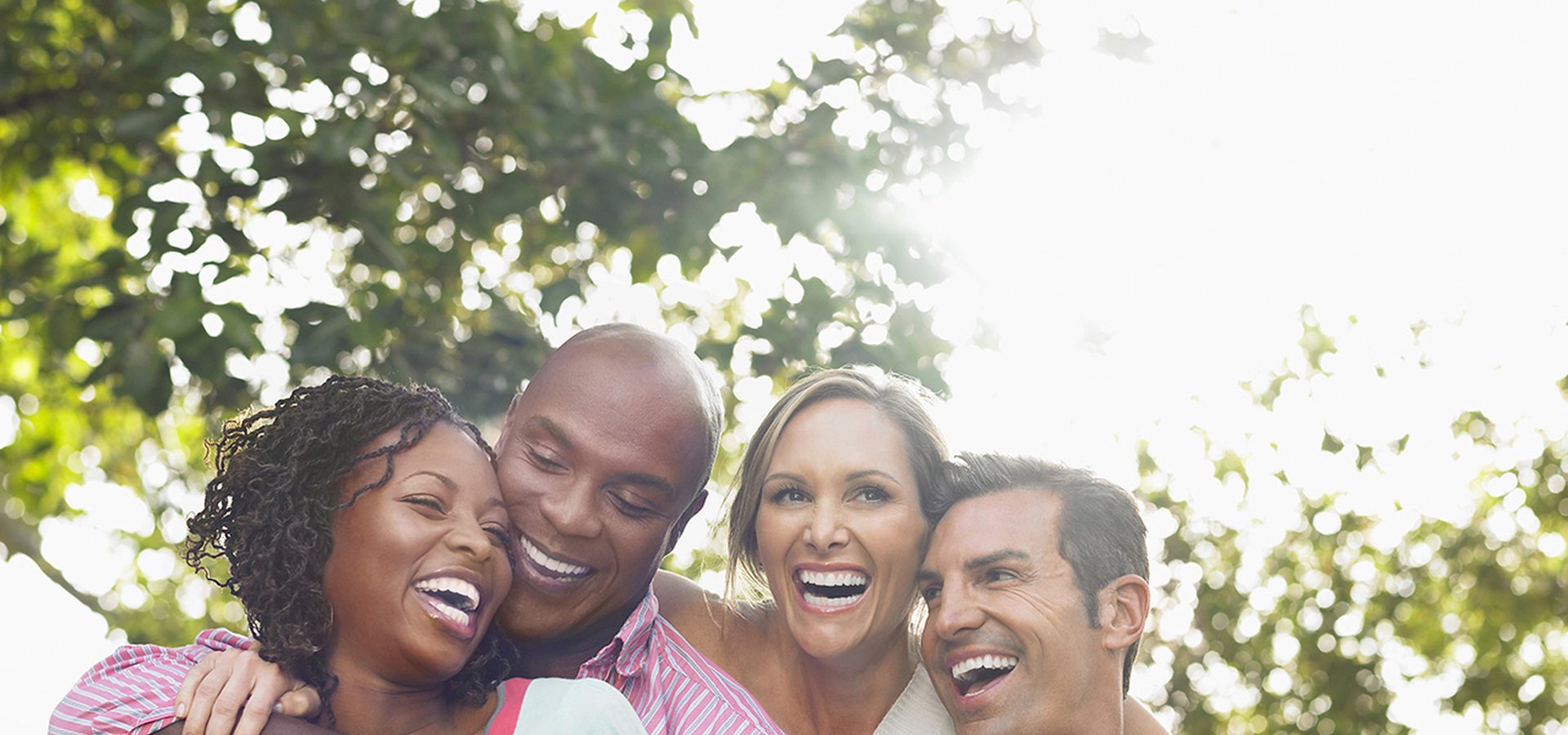 Two cheerful multiethnic couple embracing and laughing in garden